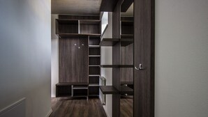 A narrow hallway with a built-in closet featuring multiple shelves and hanging spaces. - Hotel & Bistro 63 (Poprad)