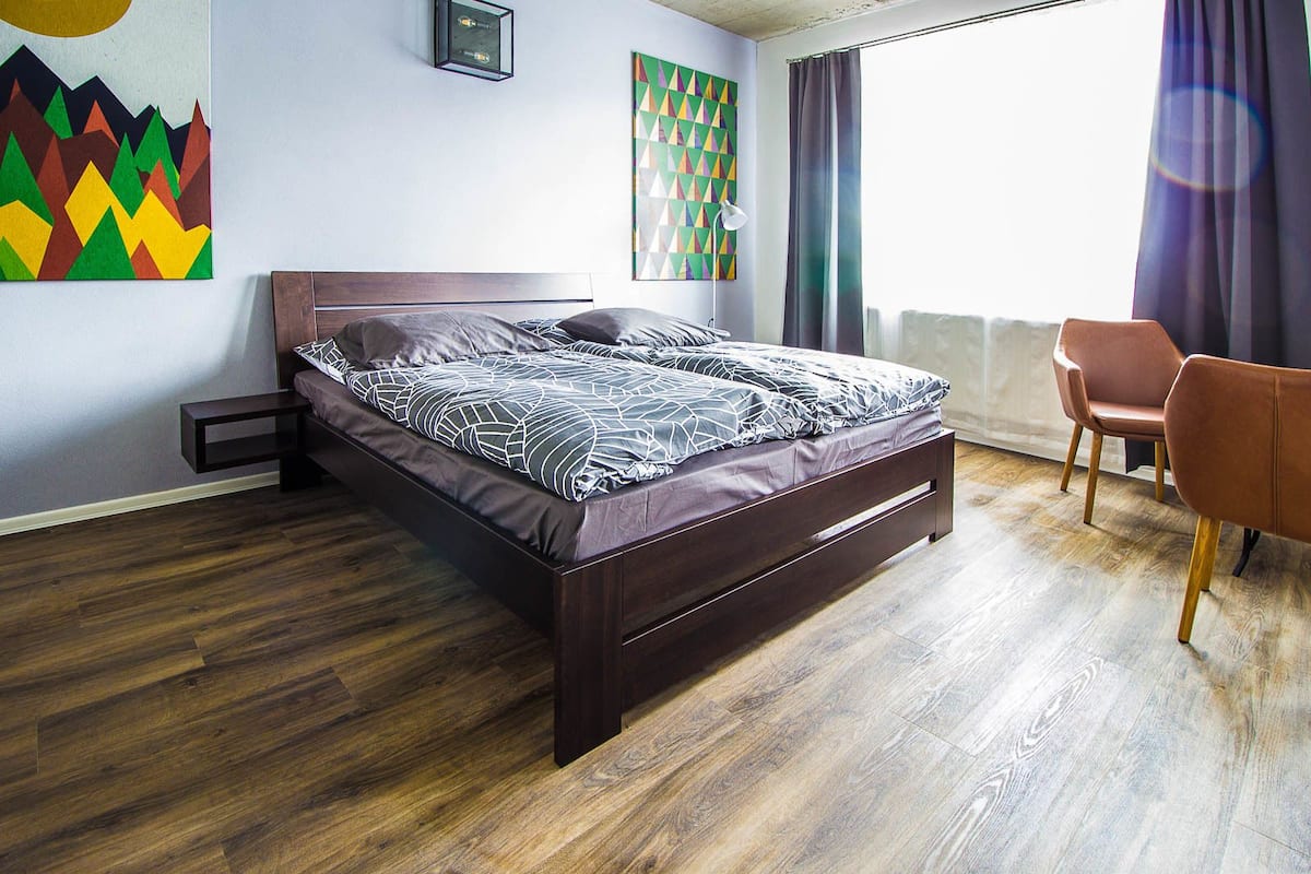 Un dormitorio moderno con una cama de madera, una mesita de noche pequeña y una silla.