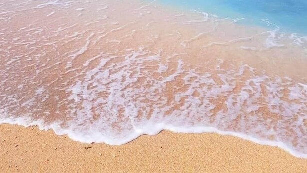 A beach with clear turquoise water and a sandy shore.
