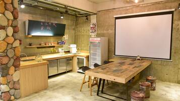 Una cocina con una mesa de madera, taburetes, una pizarra y un refrigerador.