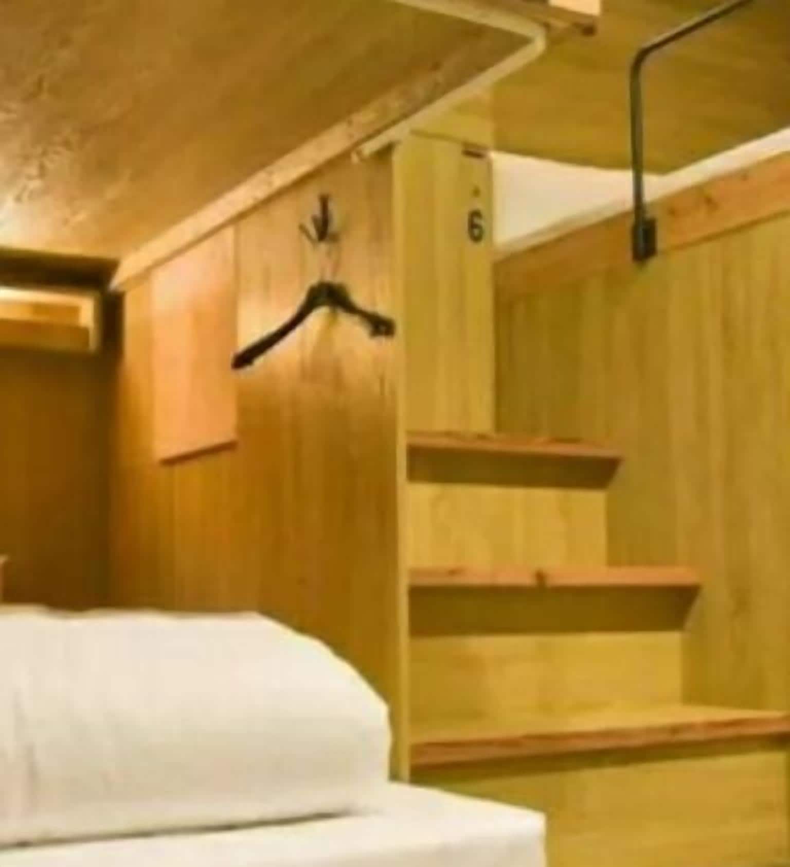Een houten interieur met een bed, een houten wandrek en een trap.