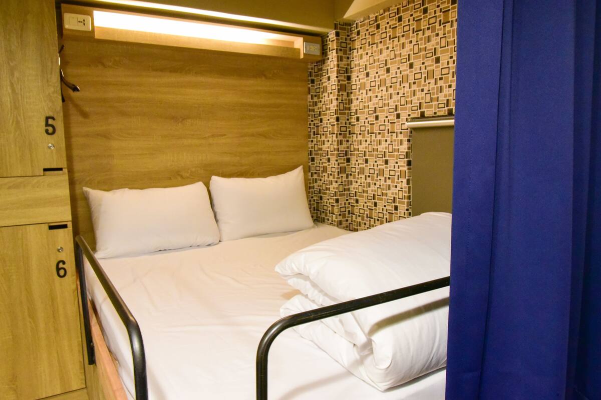 A single bed with a wooden headboard and a patterned wall.