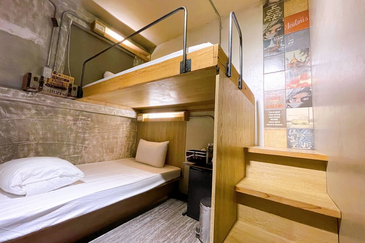 A compact bunk bed room with a small desk and a poster on the wall.