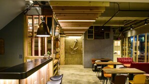 A restaurant with a bar area, wooden ceiling, and a stone wall with an anchor decoration.