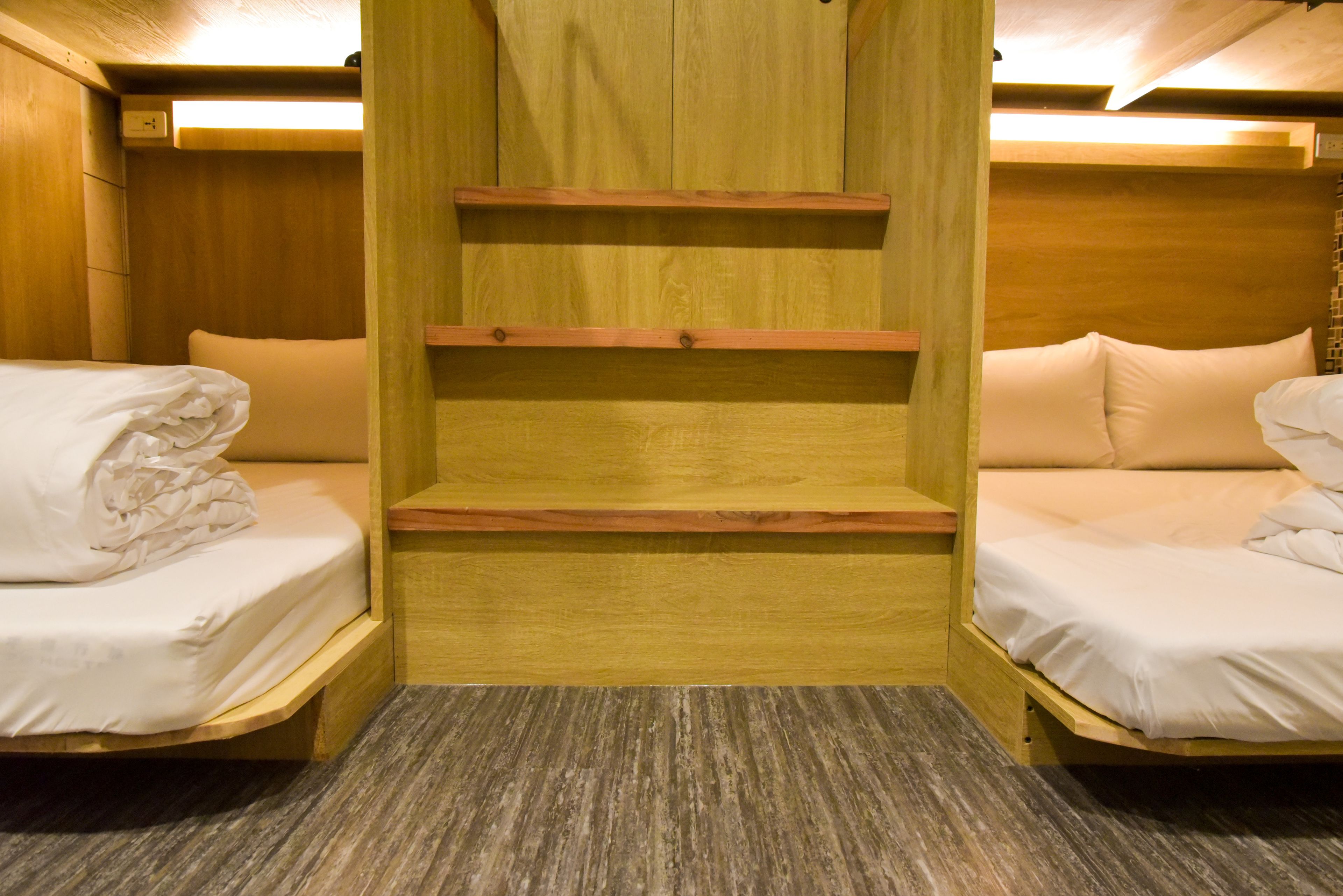 Een kleine kamer met twee bedden, houten planken en een vloerkleed.