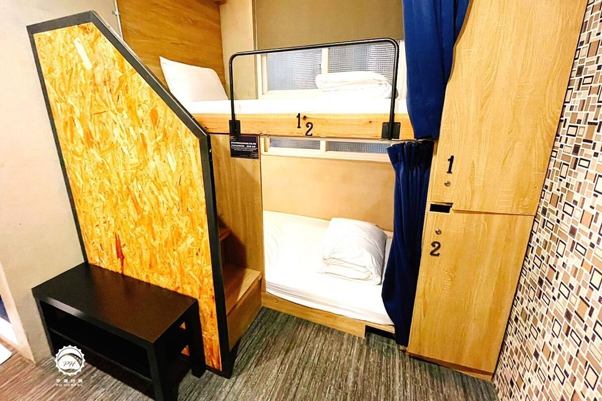 A compact hotel room with bunk beds, a small table, and a curtain.