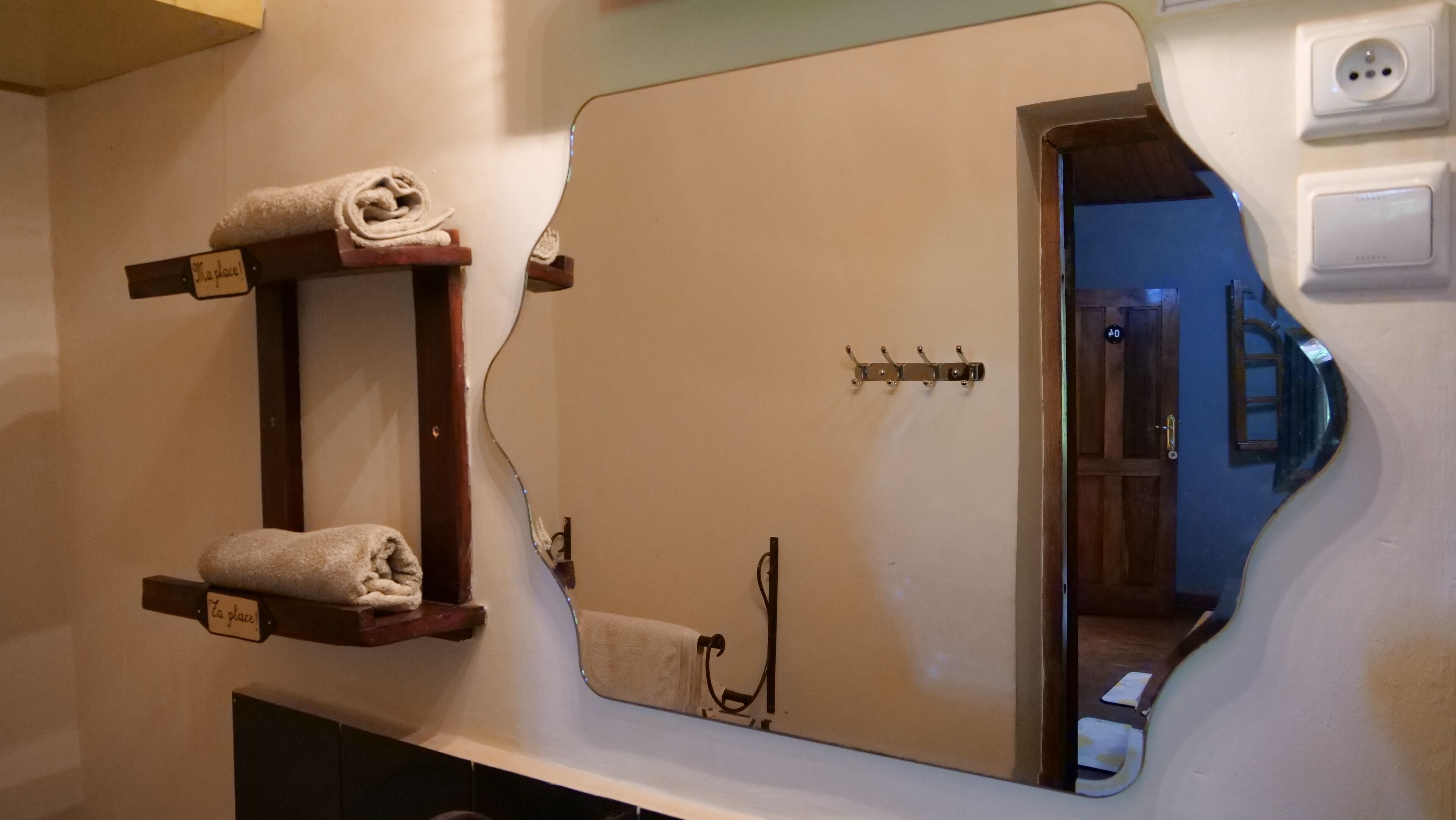 A bathroom with a large mirror, towel racks, and a door with a number plate.