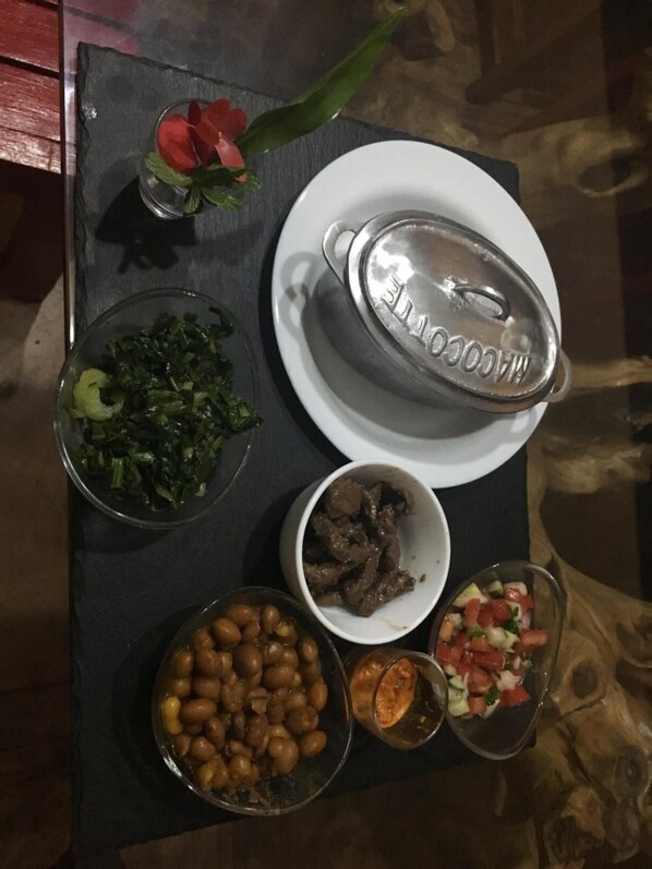 Una mesa con varios platos, incluyendo vegetales, carne, frijoles y una ensalada.