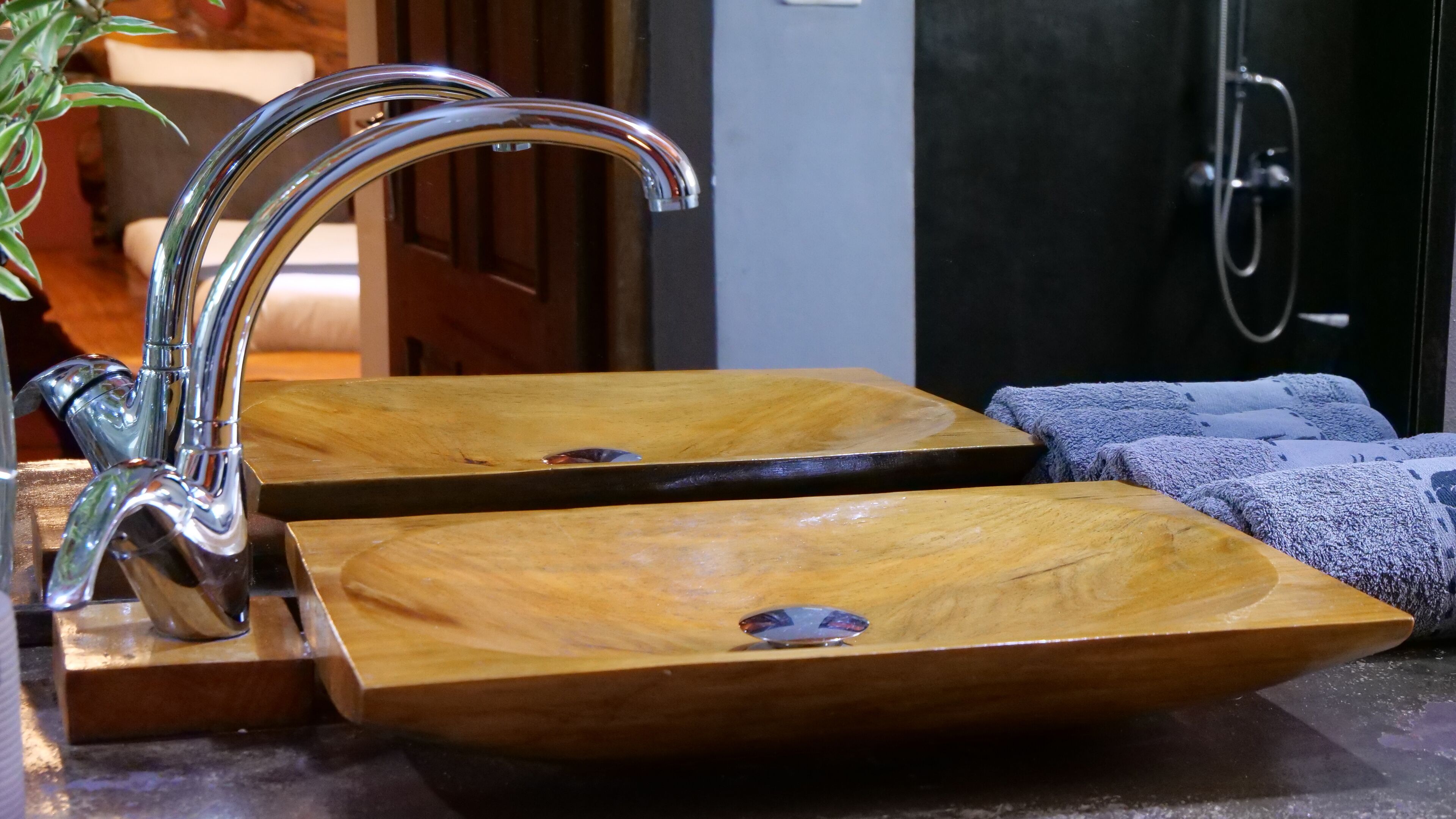 A bathroom with two wooden sinks, a chrome faucet, and a towel rack with towels.