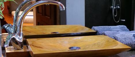 A bathroom with two wooden sinks, a chrome faucet, and a towel rack with towels.