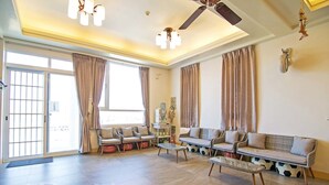 A spacious living room with a high ceiling, a ceiling fan, and large windows with curtains. There are two sofas and a coffee table. - Moon Fish (Magong)