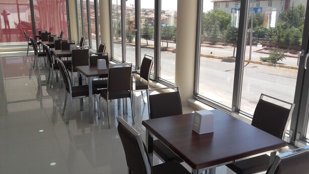 Un espace de restauration intérieur moderne, doté de cloisons en verre, de chaises et de tables en métal.