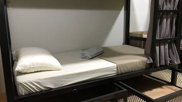 A bunk bed with a white mattress, a pillow, and a folded towel.