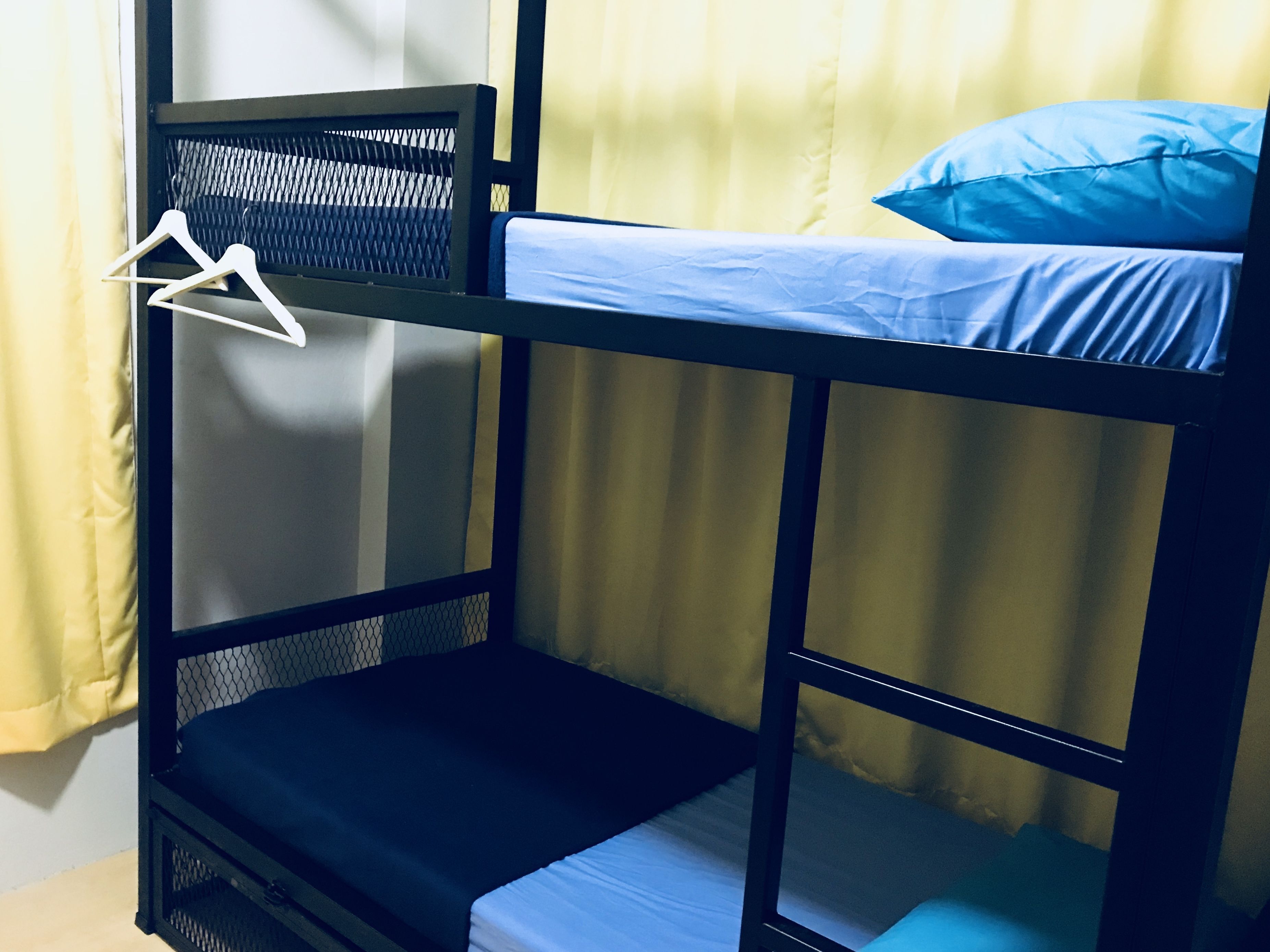A bunk bed with a mesh shelf and a hanging clothes rack.