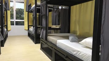 A dormitory-style room with bunk beds, a window, and curtains.