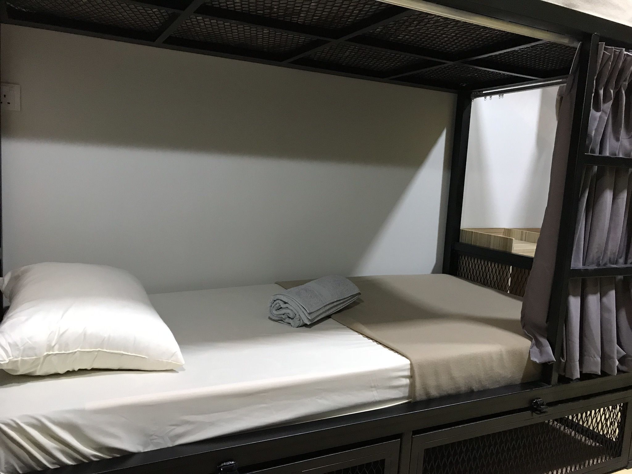 A single bed with white bedding, a folded towel, and a white pillow.