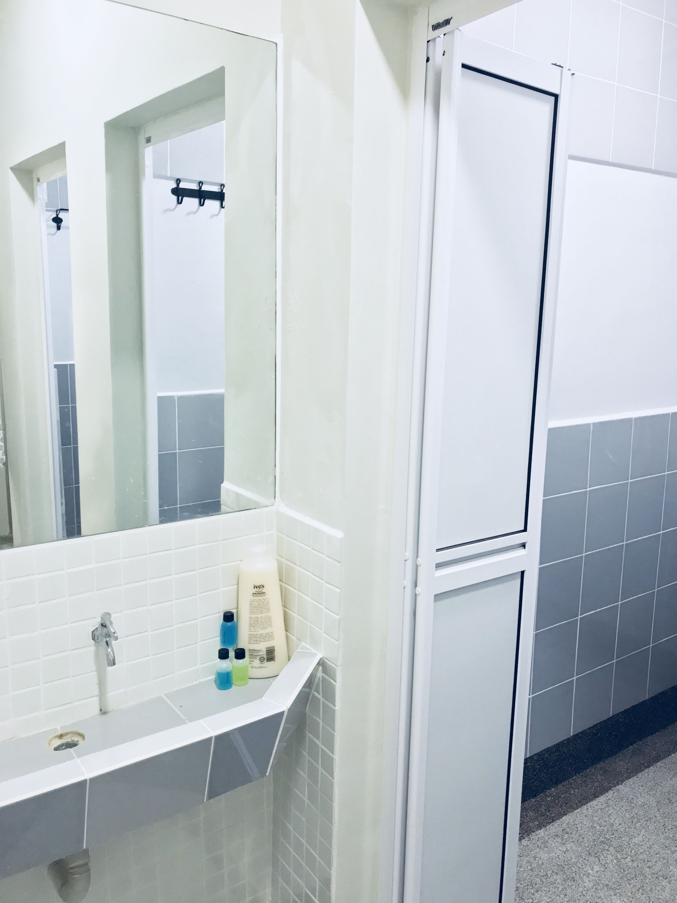 Casa de banho com lavatório branco, espelho e zona de duche.