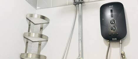 A shower with a handheld showerhead, a wall-mounted control panel, and a step stool.