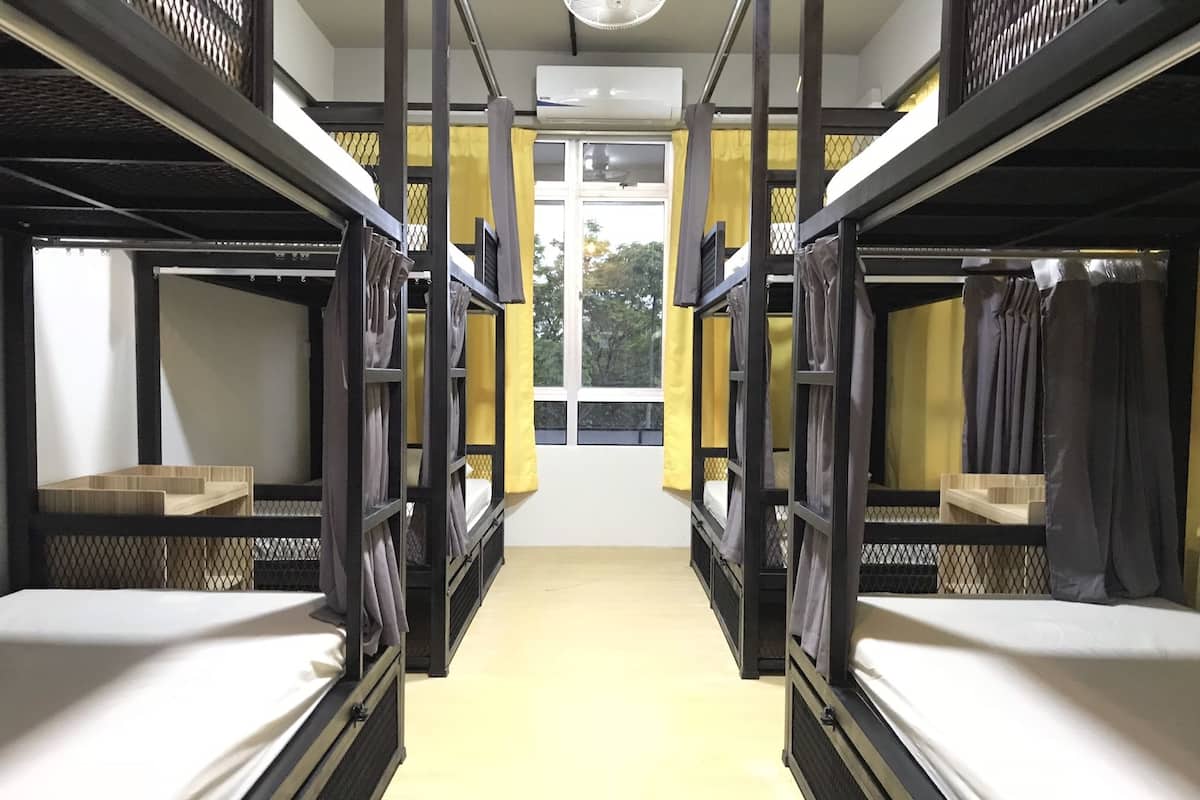 Une chambre de dortoir avec des lits superposés, une fenêtre avec des rideaux jaunes et un climatiseur fixé au mur.