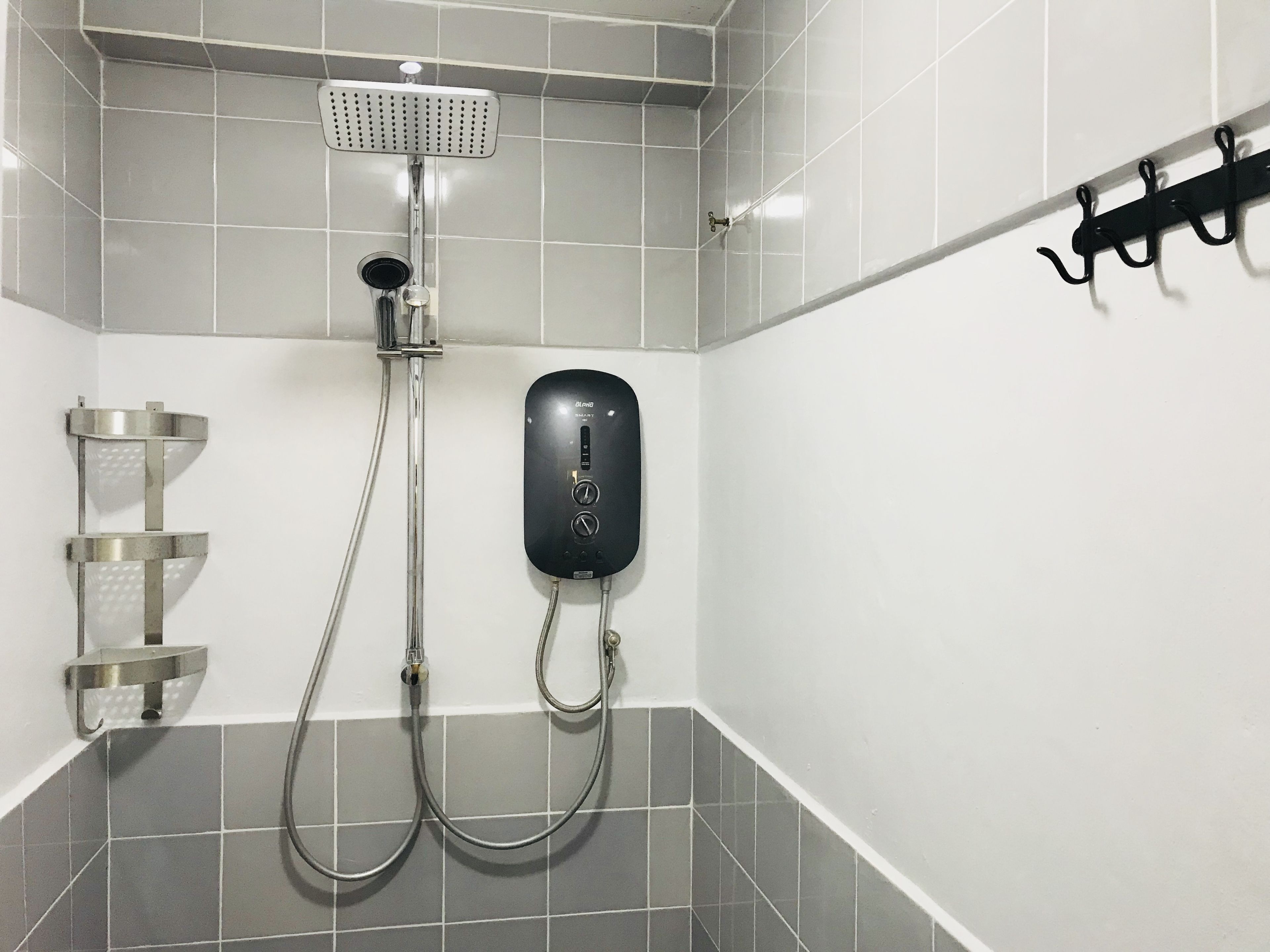 A modern bathroom with a shower, a handheld showerhead, a wall-mounted control panel, and a towel rack.