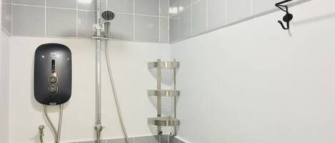 A shower area with a handheld showerhead, a wall-mounted control panel, and a handheld shower attachment.