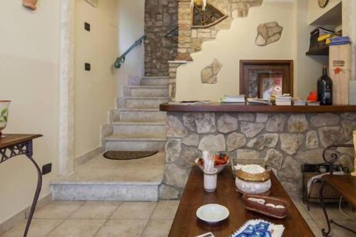 A dining area with a stone fireplace, a staircase, and a wooden table with food items.