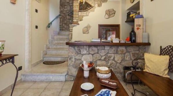 A dining area with a stone fireplace, a staircase, and a wooden table with food items. - Al Campanaro Bed & Breakfast (Taurasi)