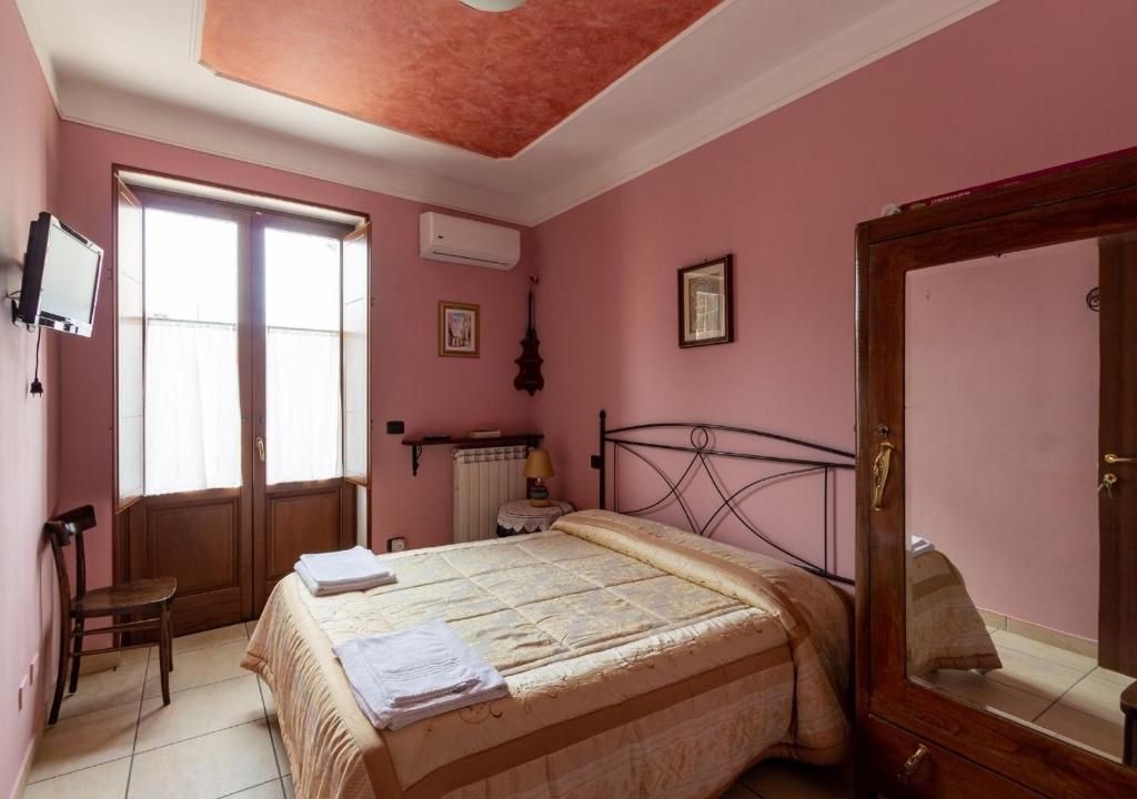 Un dormitorio con una cama, una silla, un televisor y un espejo.