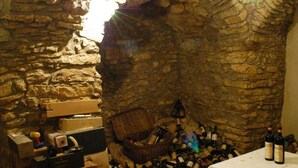 A stone-walled cellar with wine bottles and boxes.