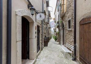 A narrow cobblestone street with stone buildings, a wooden door, and a bench. - Al Campanaro Bed & Breakfast (Taurasi)
