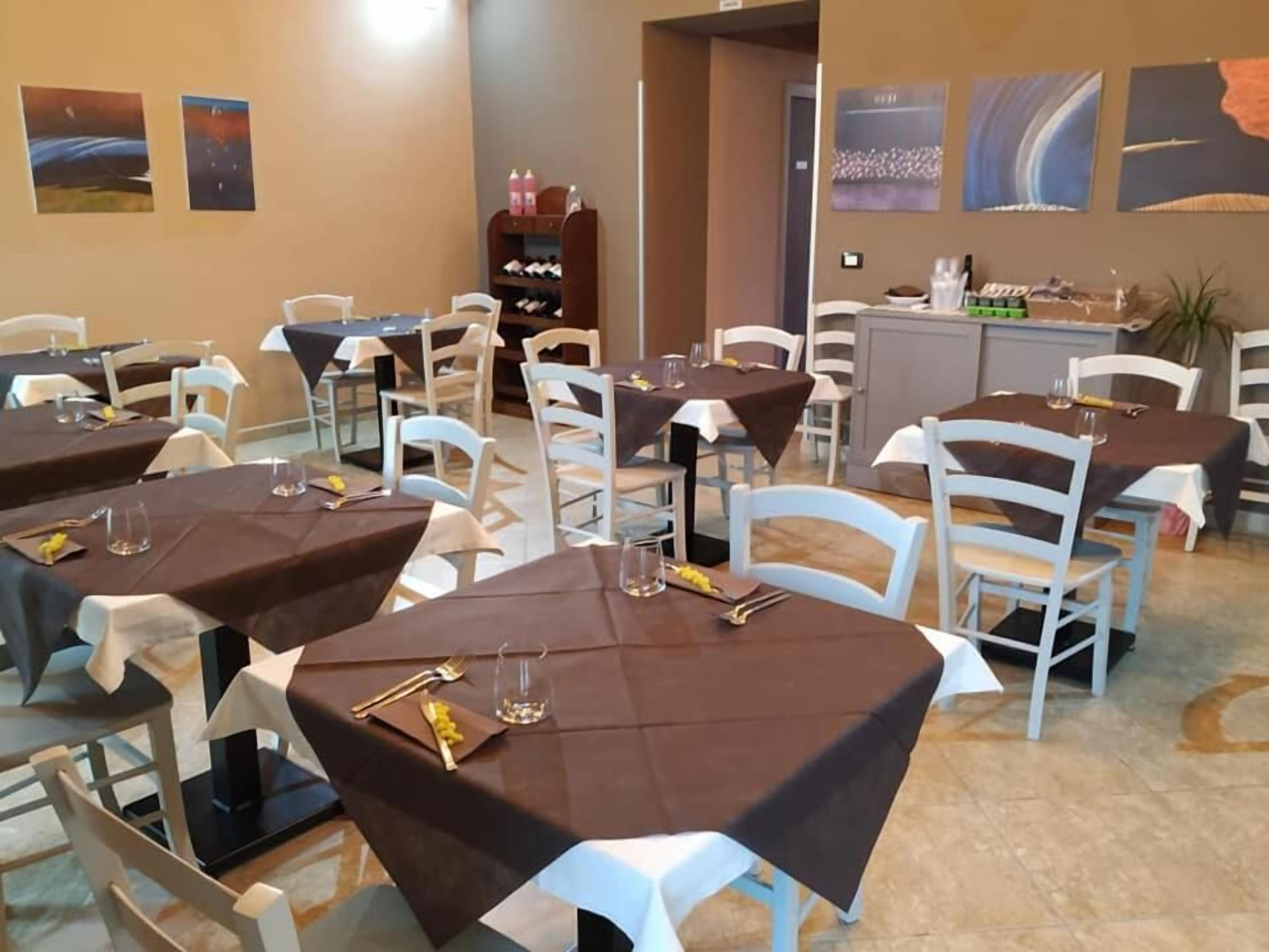 A restaurant with multiple tables, each covered with a brown tablecloth and white chairs.