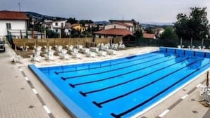 A swimming pool with multiple lanes, surrounded by lounge chairs and a tiled deck.