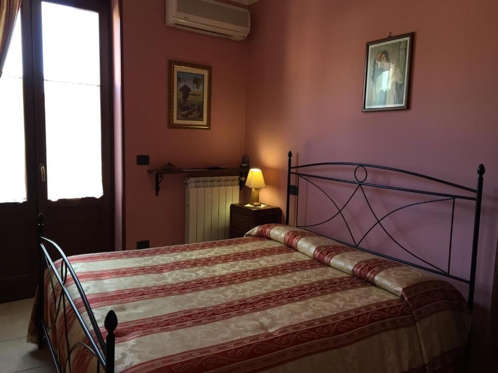 Ein Schlafzimmer mit einem Bett, einem Nachttisch, einer Lampe und einem Fenster.