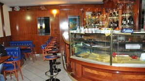 Un'area bar con decorazioni in legno, una vetrina in vetro e una zona con sedute blu.