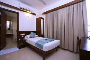 Una habitación de hotel con cama, mesita de noche y escritorio.