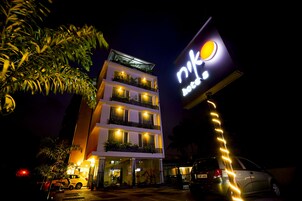 Un hotel de varios pisos con un cartel iluminado llamativo, iluminación exterior y un coche estacionado.