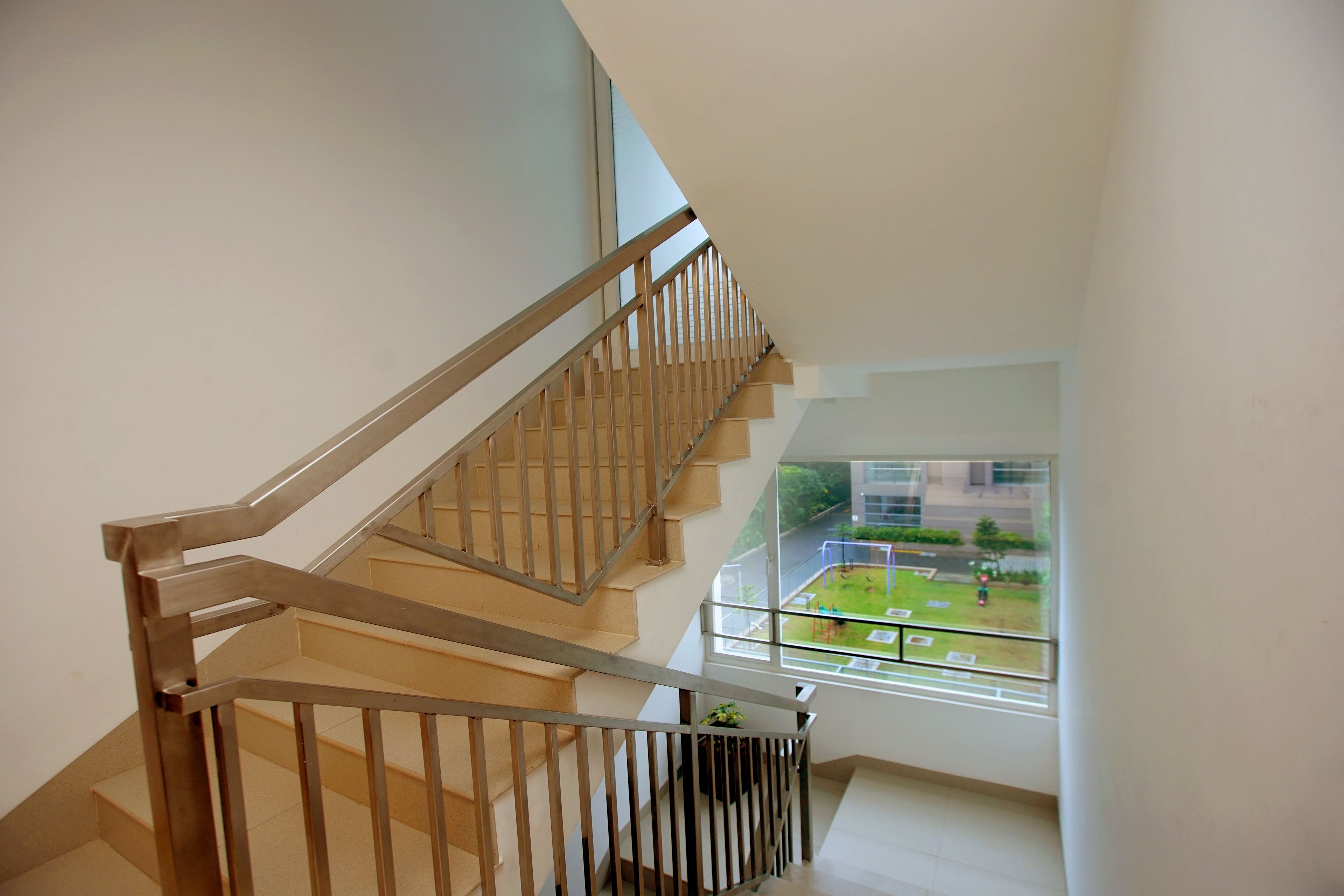 A modern interior with a wooden staircase and a large window offering a view of a green outdoor area.