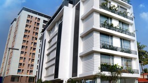 A modern multi-story hotel with balconies, large windows, and a parking area. - Niko Hotels (Kanayannur)