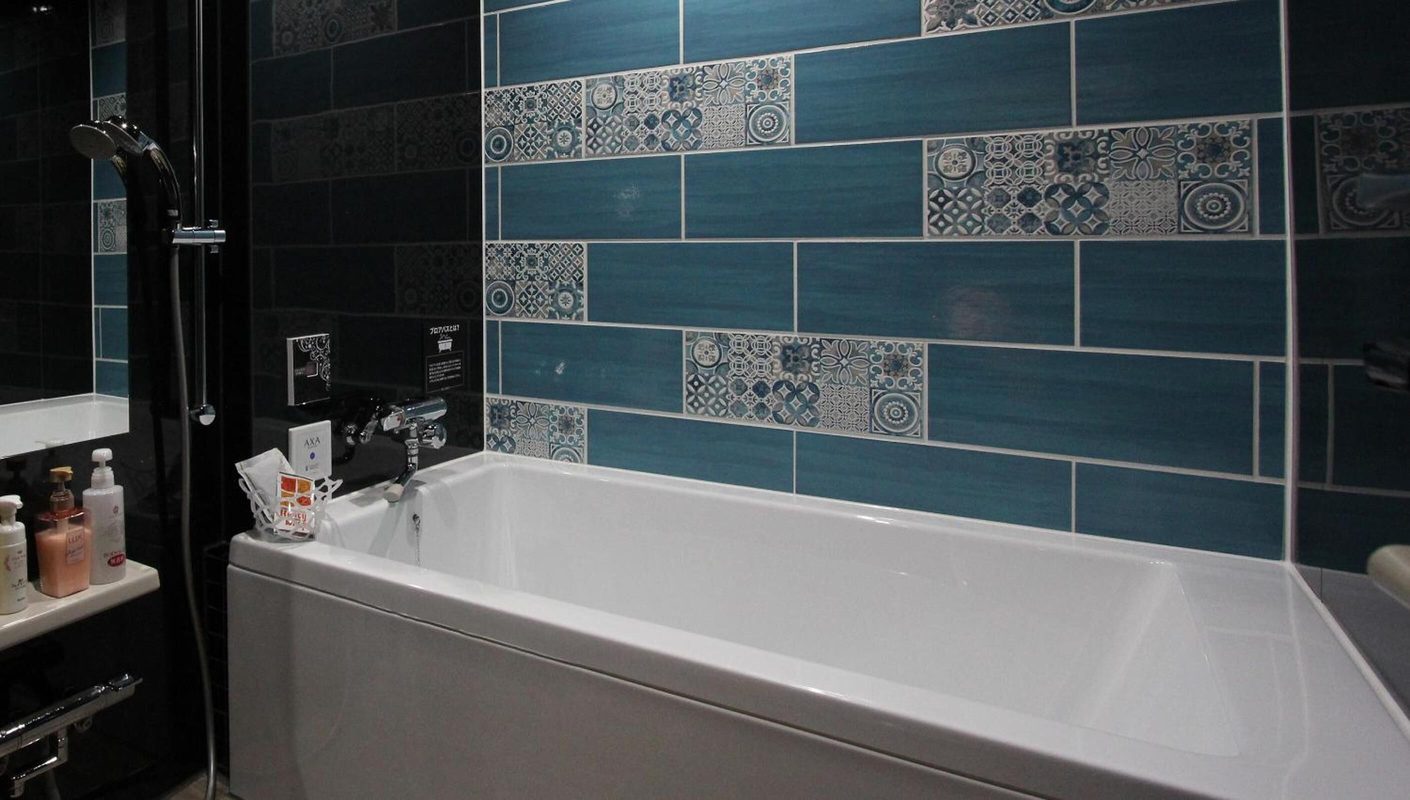A bathroom with a white bathtub, a black shower, and a tiled wall with blue and white patterns.
