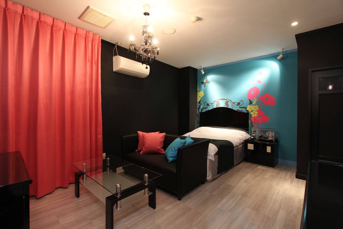 Une chambre d’hôtel avec un lit, un canapé, une table basse en verre et un lustre.