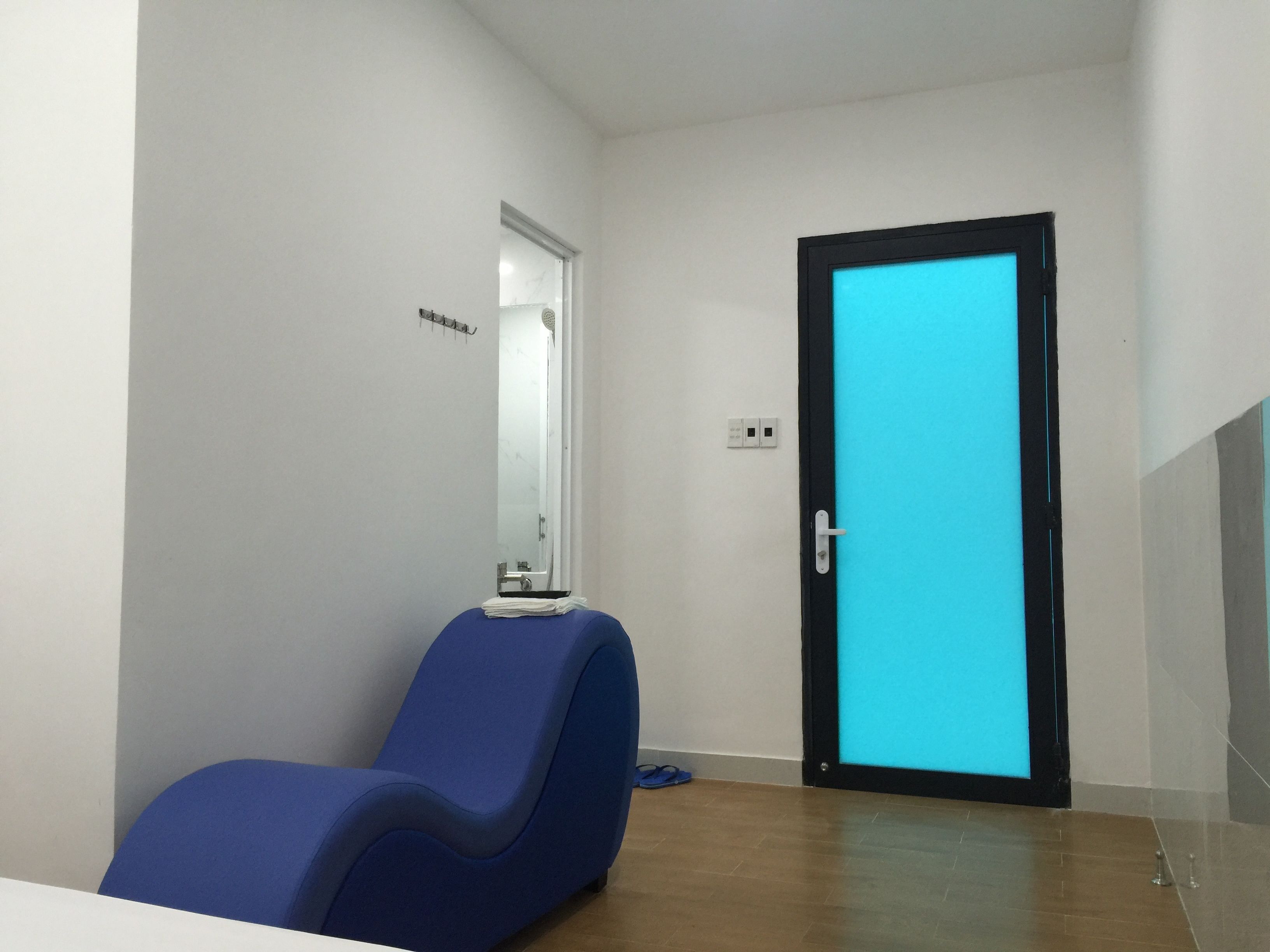 A room with a blue chair, a door with a blue screen, and a small table with a mirror.