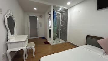 Un dormitorio con cama, cómoda, espejo, ducha y puerta que da a un baño.