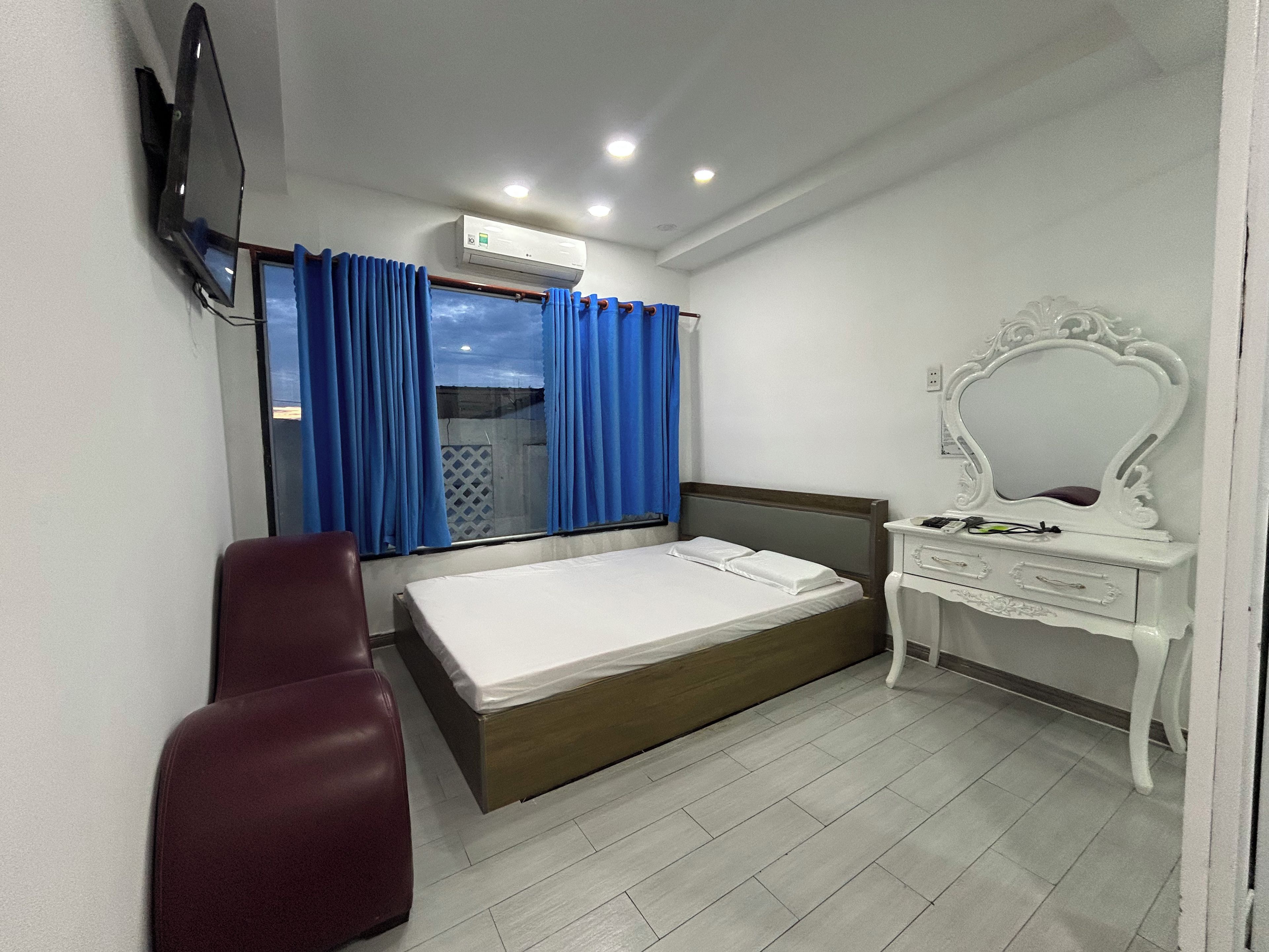 Un dormitorio con cama, escritorio, silla, televisi ón y unidad de aire acondicionado.