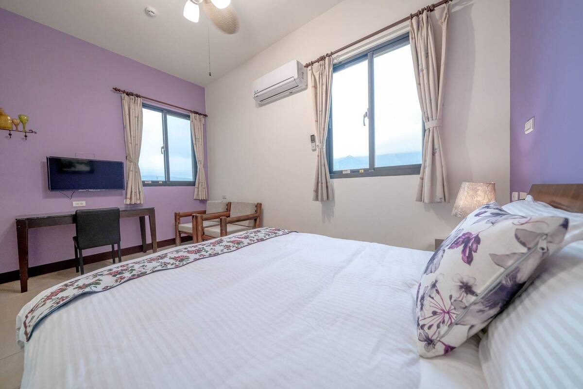 A bedroom with a bed, a desk, a chair, and a TV.