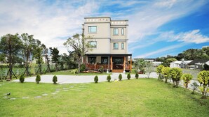A modern two-story house with a front porch, surrounded by a well-maintained lawn and small trees. - Bo Jue Farm Stay (Ji'an)