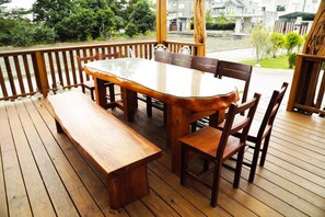 A wooden deck with a table and chairs, a bench, and a railing. - Bo Jue Farm Stay (Ji'an)