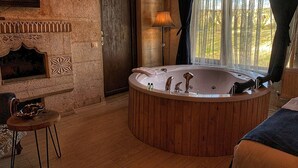 A spacious bathroom with a large freestanding bathtub, a wooden vanity, and a stone wall.