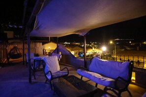 An outdoor seating area with a covered section and a view of the city at night. - Rose Valley Hotel (Avanos)