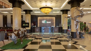 Un vestíbulo de hotel con piso a cuadros, un mostrador de recepción y una araña.