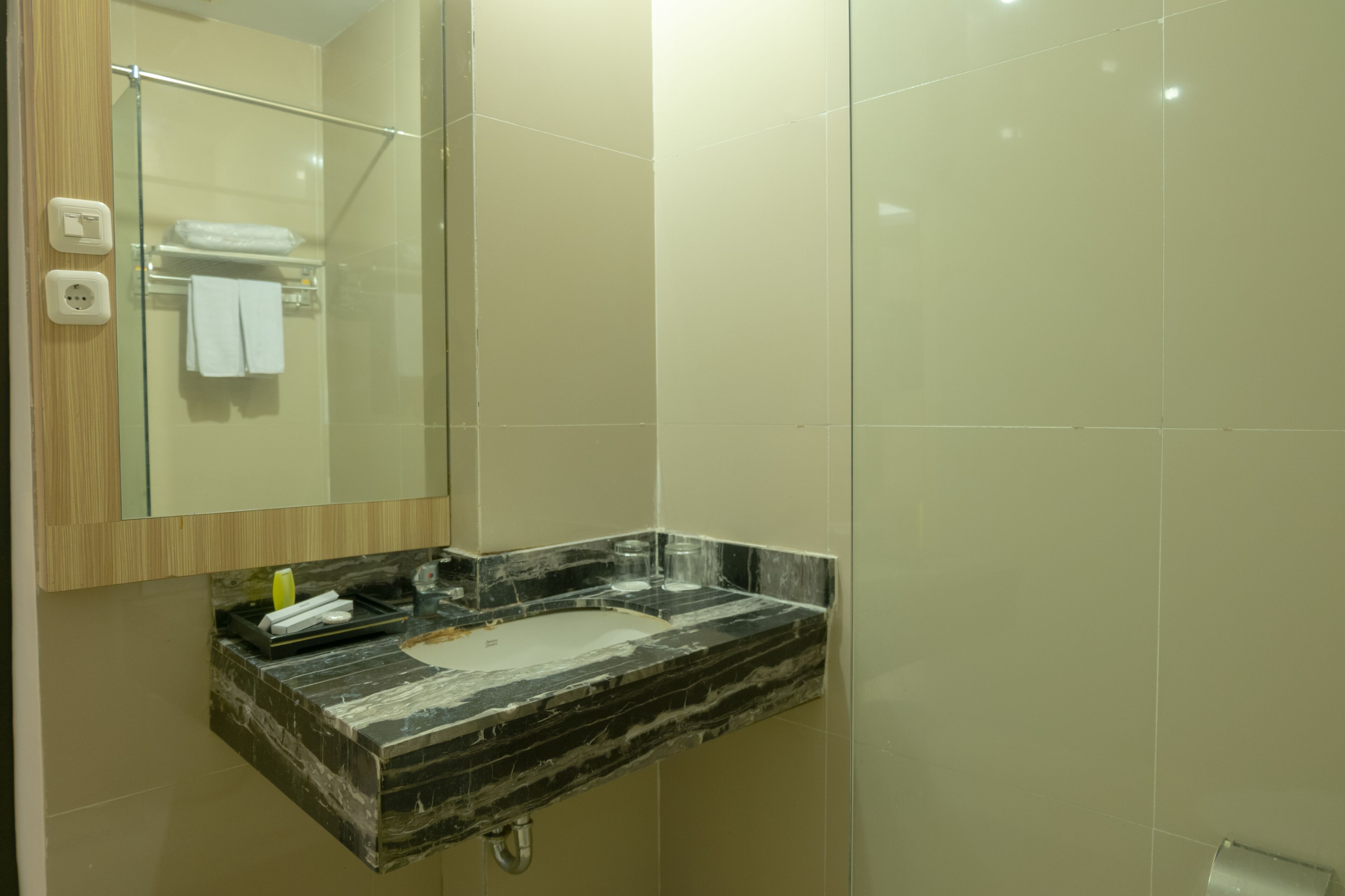A bathroom with a marble sink, a glass shower enclosure, and a mirror above the sink.